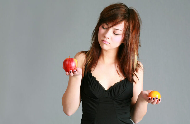 photo d'une femme comparant une pomme et une orange français