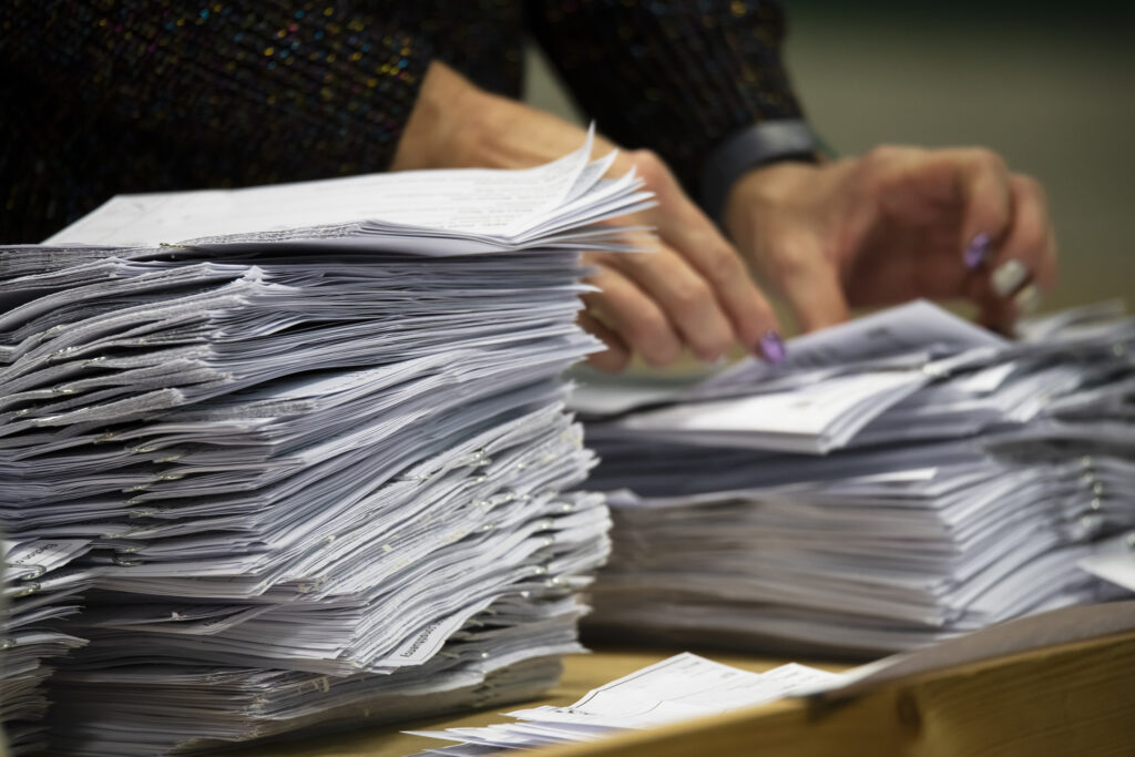 A pair of hands counting piles of ballot papers during an election/une paire de mains comptant des piles de bulletins de vote lors d'une élection